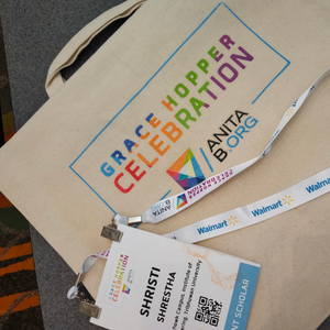 a picture of a tote bag with Grace Hopper Celebration logo and Shristi's event participant card