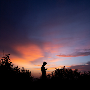 a silouhette of a person in an outdoor setting in the evening with beautiful sky in the background