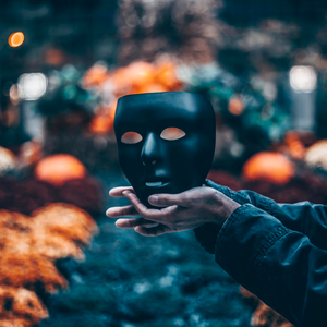 a mask holded by a pair of hands with an outdoor background