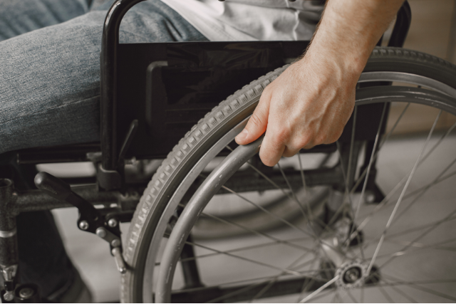 an zoomed image of a person sitting on wheelchair focused on his hands on the wheels